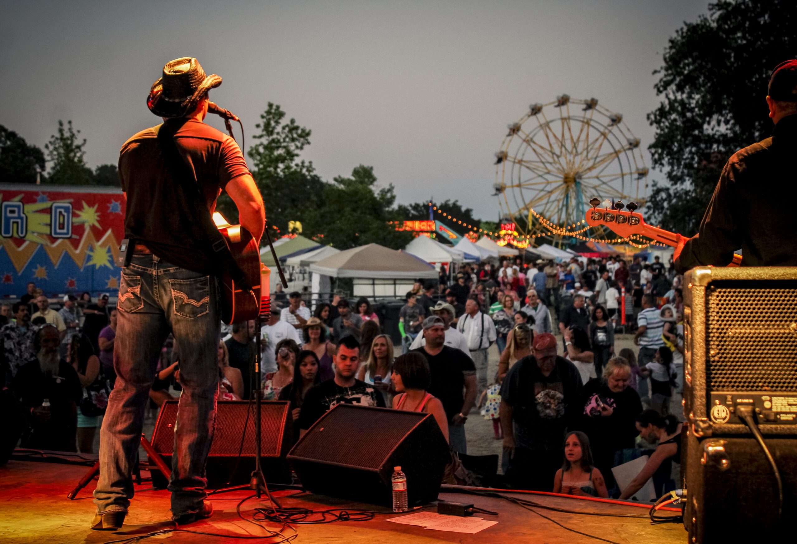 A Person Playing Guitar On A Stage With A Crowd Of People