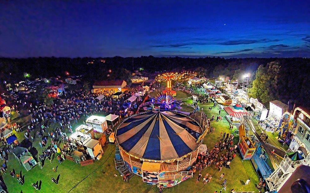 A Large Crowd Of People At A Fair